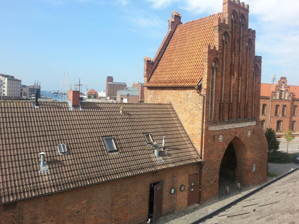 A historic brick building with a tiled roof and a prominent tower.