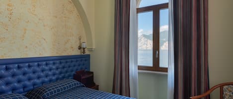 Una habitación con una cama grande, una ventana con cortinas y vistas a las montañas.