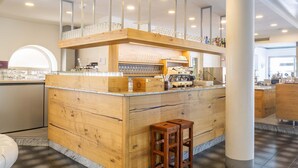 A bar area with wooden counter and stools, a coffee machine, and glassware. - Hotel Malcesine (Malcesine)