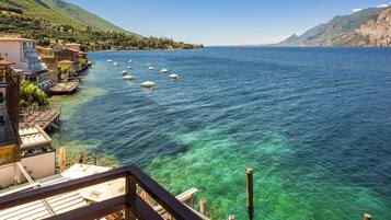 A coastal view with clear blue water, boats, and a building with a balcony overlooking the sea.