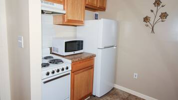 A compact kitchen with a stove, microwave, and refrigerator.