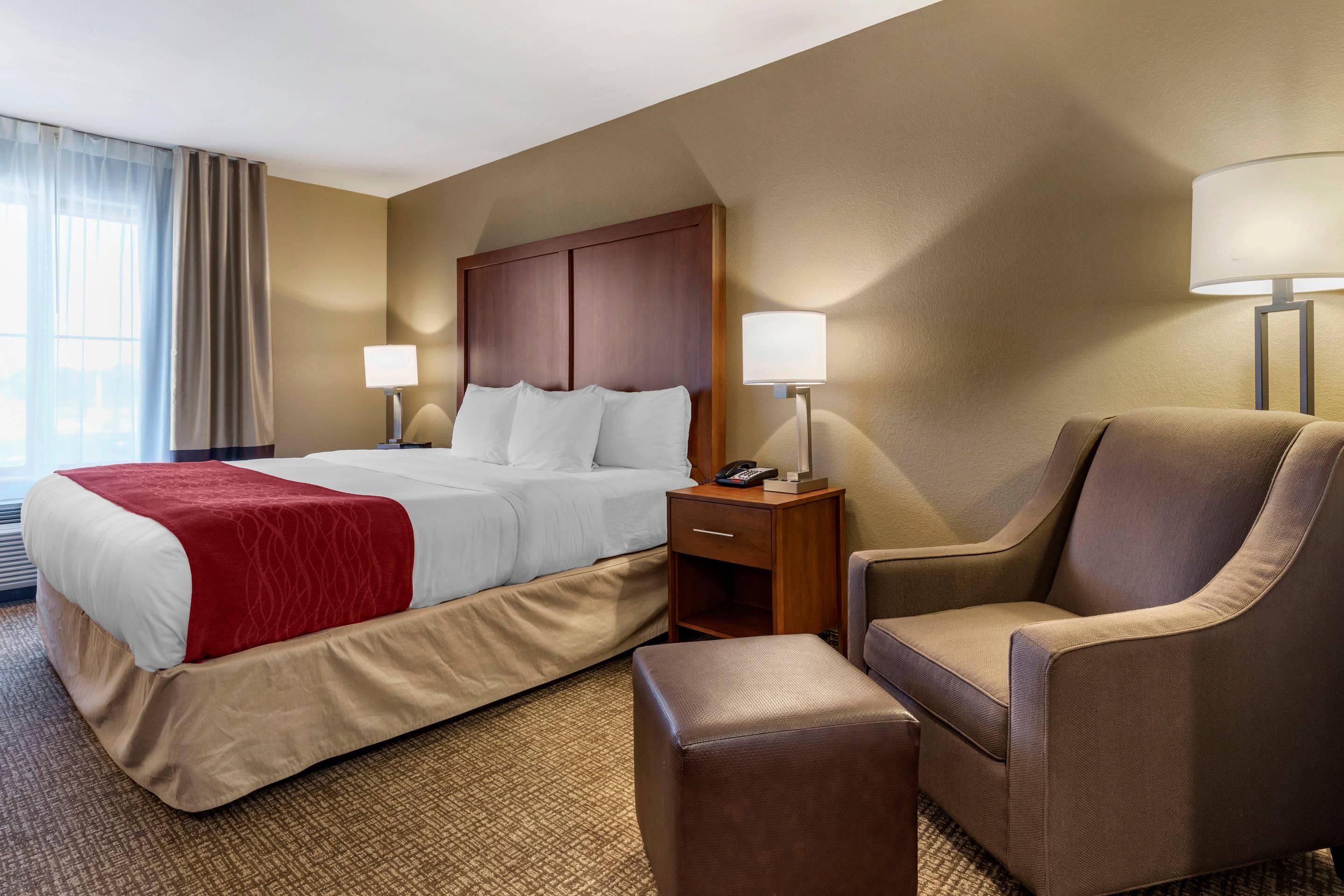 A hotel room with a bed, bedside tables, a chair, and a lamp.