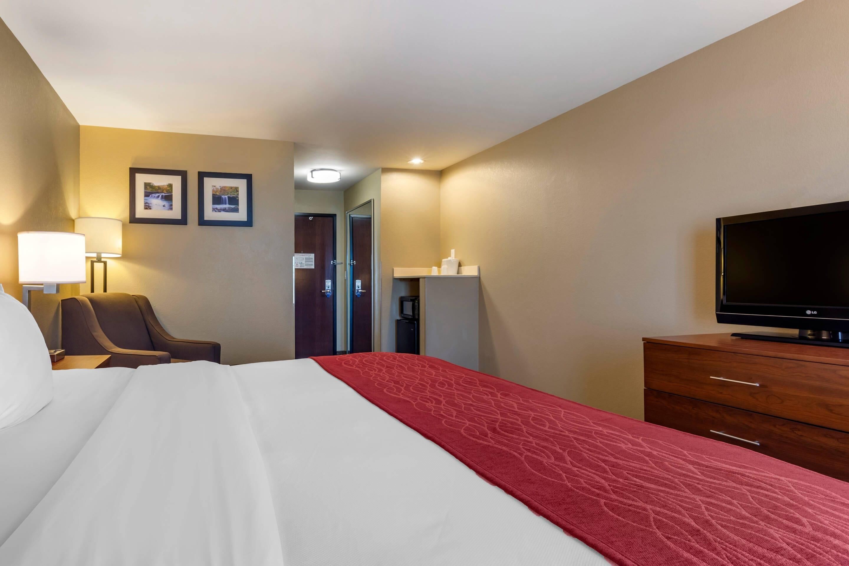 A hotel room with a bed, a TV, a desk, and a chair.