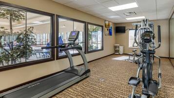 Un gimnasio con cinta de correr, elíptica y bicicleta estática.