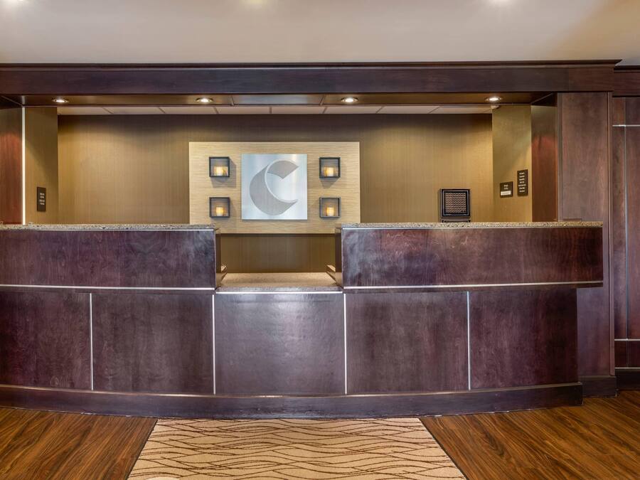 A reception desk with a modern design, featuring a central wall-mounted artwork and recessed lighting.