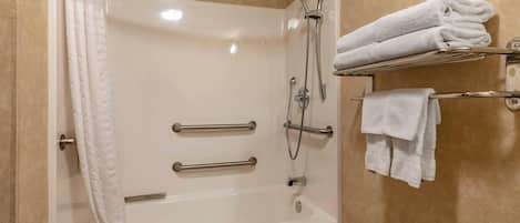 A shower with a glass door, a towel rack with folded towels, and a shower head.