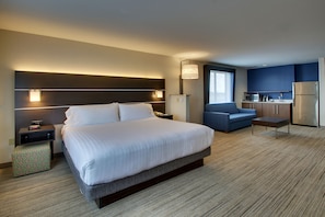 Habitación de hotel con una cama grande, un escritorio, una silla, kitchenette y una ventana.