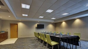 Une salle de conférence avec une longue table, des chaises, un téléviseur à écran plat et des bouteilles d’eau posées sur la table.