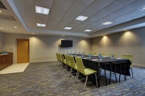 A conference room with a long table, chairs, a flat-screen TV, and water bottles on the table. - Holiday Inn Express & Suites Morris by IHG (Morris)