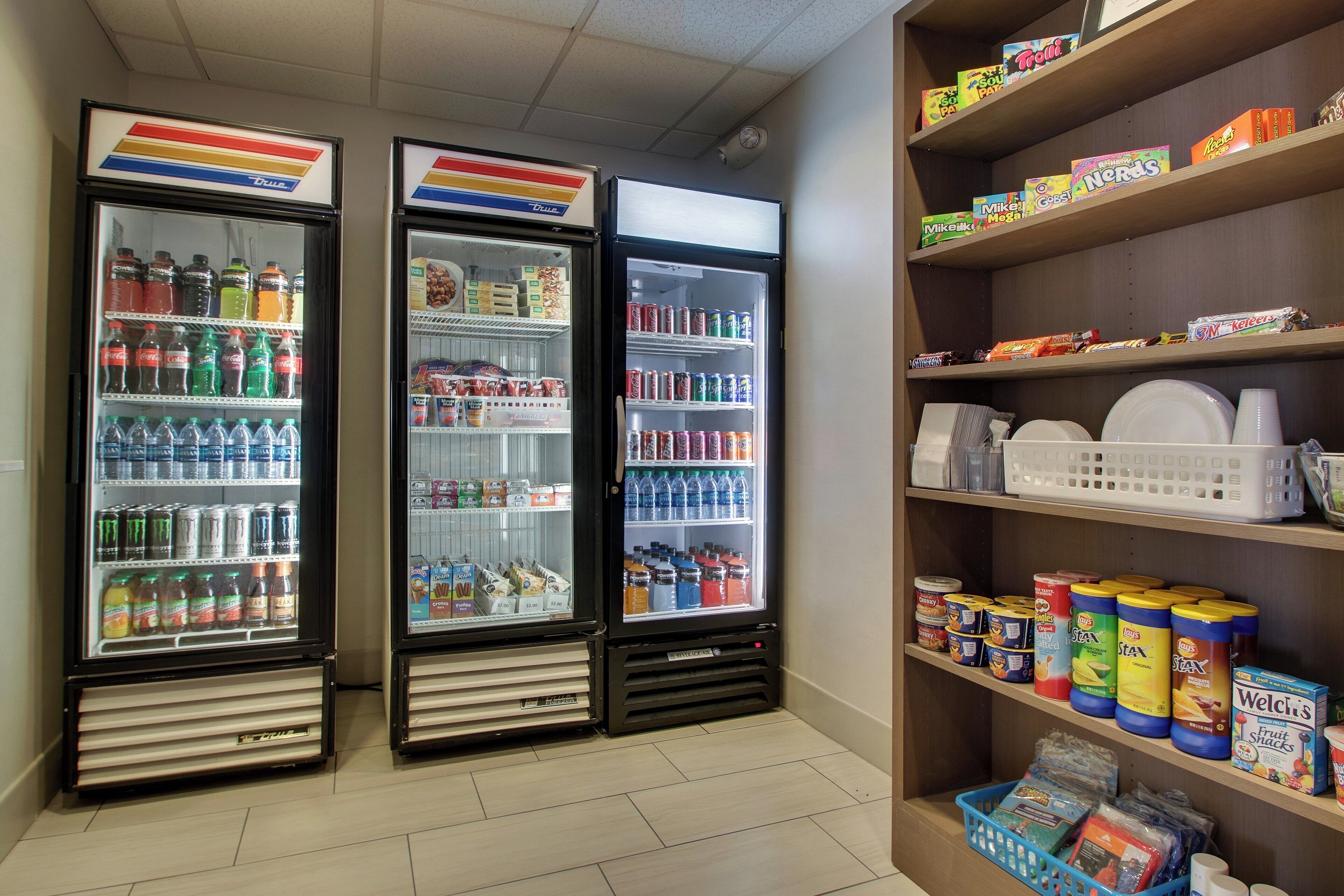 Un espace de vente proposant deux distributeurs de boissons et une étagère remplie de collations et de condiments.