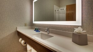 Une salle de bain avec un grand miroir, un lavabo et un distributeur de serviettes.