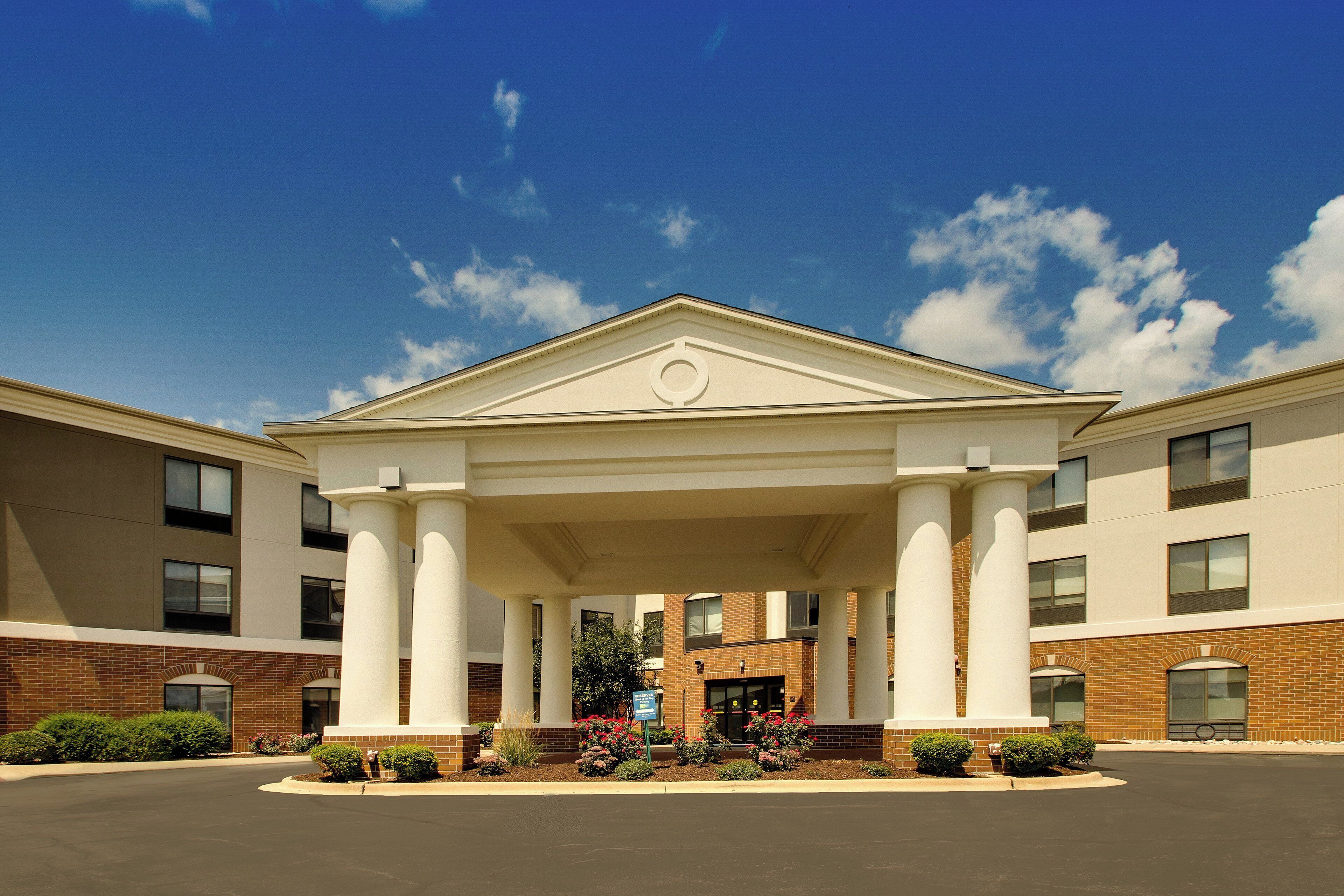 A hotel entrance with a covered walkway, brick facade, and a clear sky.