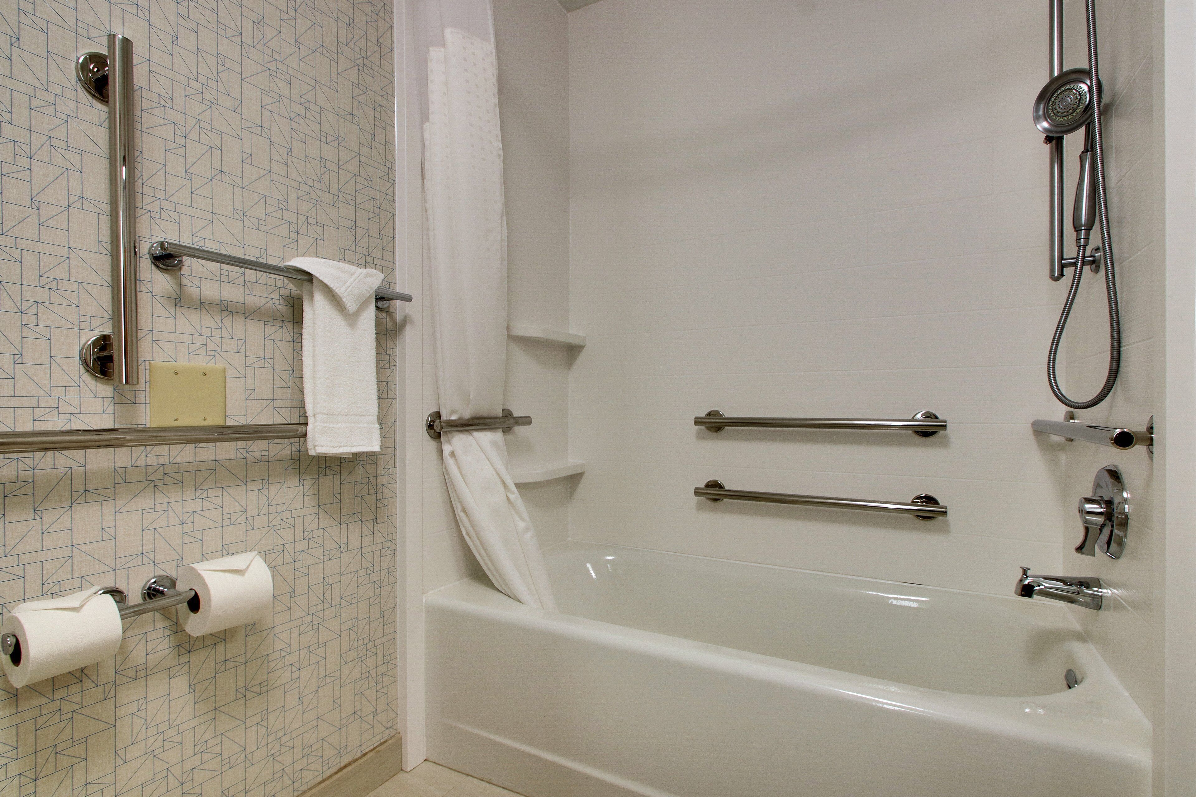 Un baño moderno con bañera, ducha y dispensador de papel higiénico.