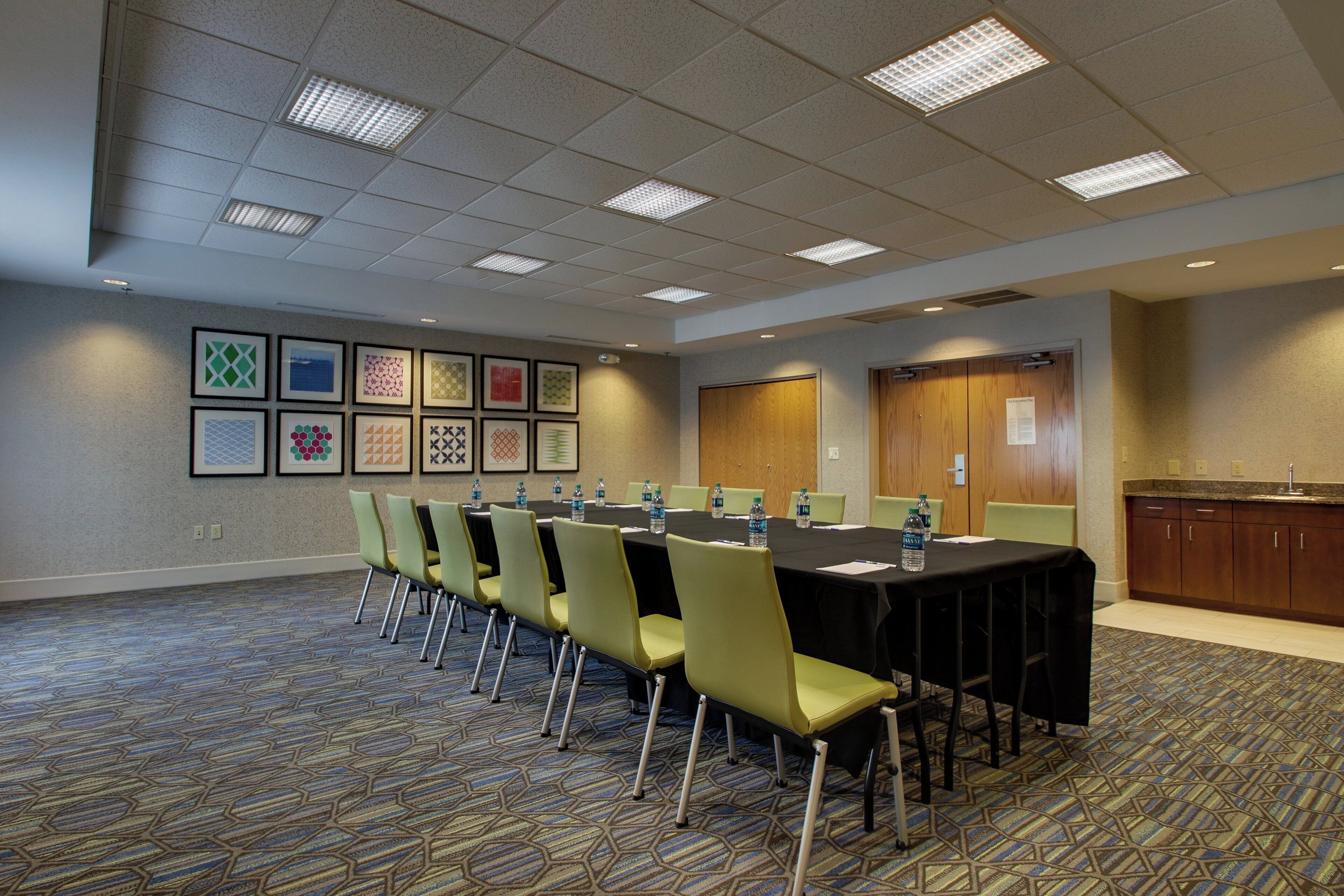 A conference room with a long table, chairs, water bottles, and framed pictures on the wall.