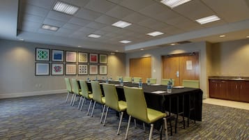 A conference room with a long table, chairs, water bottles, and framed pictures on the wall.