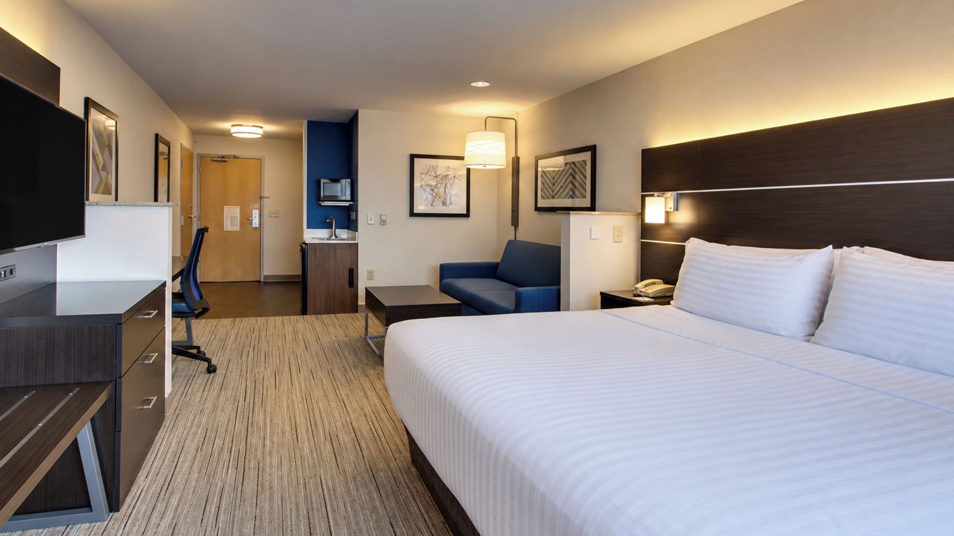 Una camera d'albergo con un letto, una scrivania, una sedia e un angolo cottura.