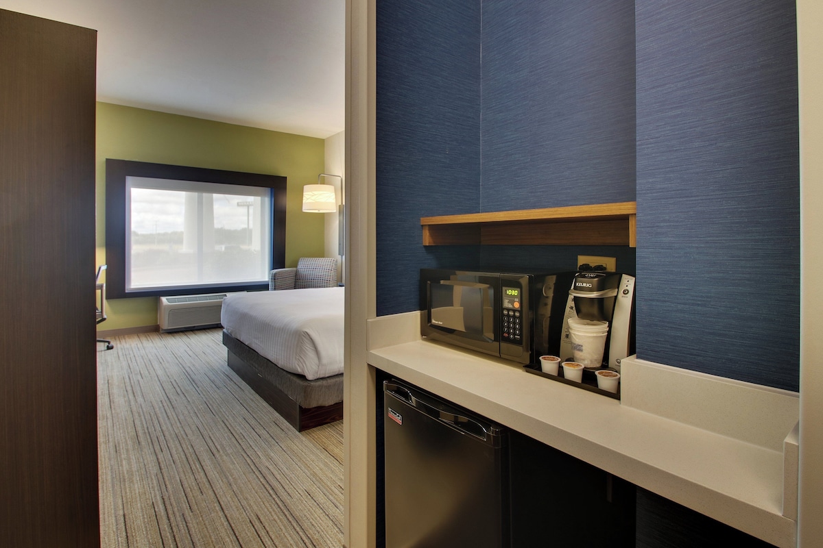 Habitación de hotel con cama, microondas, cafetera y ventana con vistas.