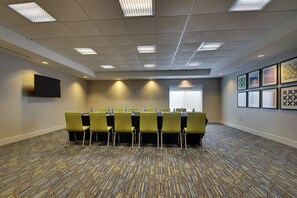 Une salle de conférence équipée d’une longue table, de chaises et d’un écran de projection.