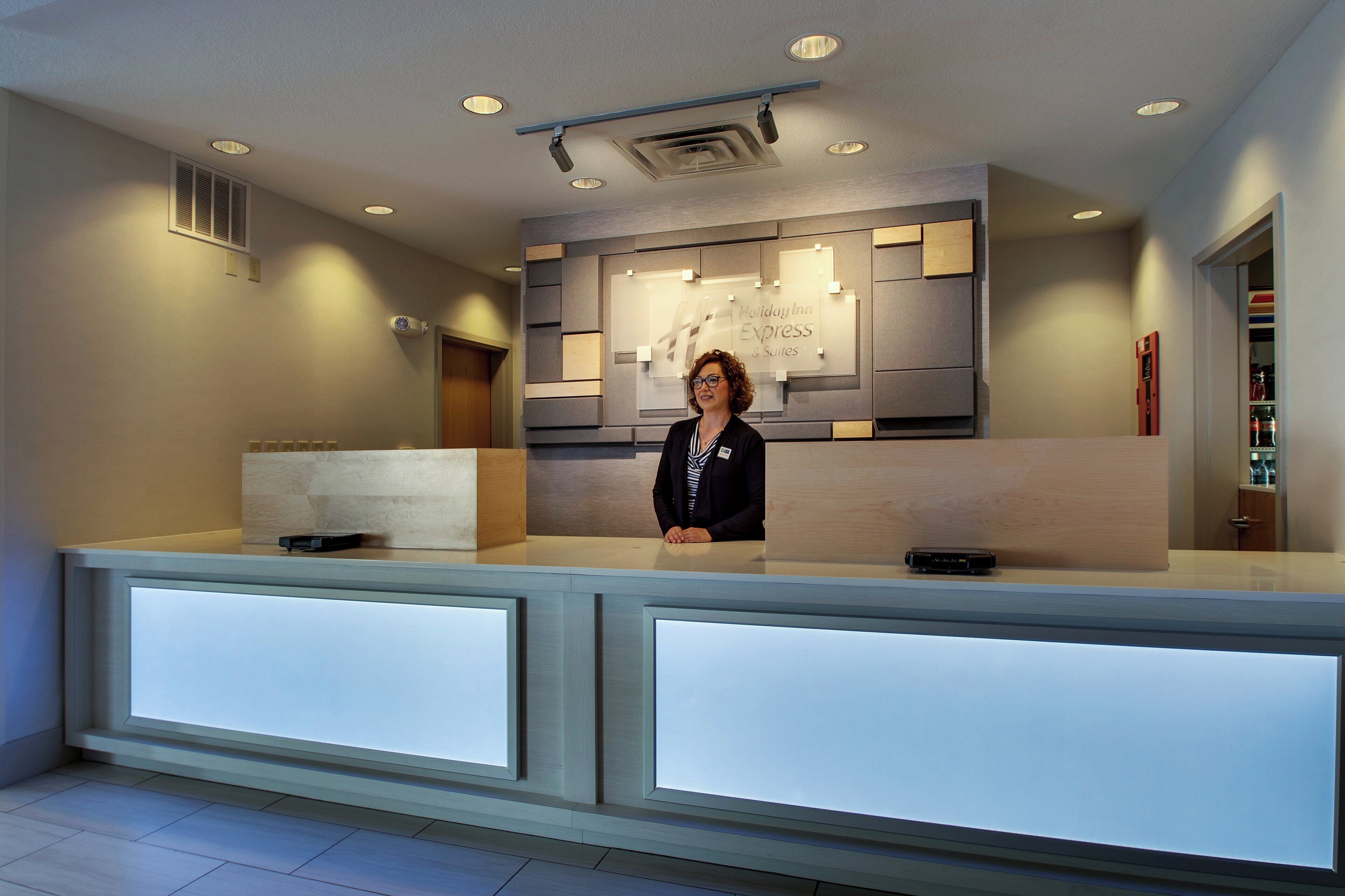 En hotellreception med modern design, en skylt som visar att det är ett Holiday Inn Express & Suites, och en övervakningskamera ovanför.