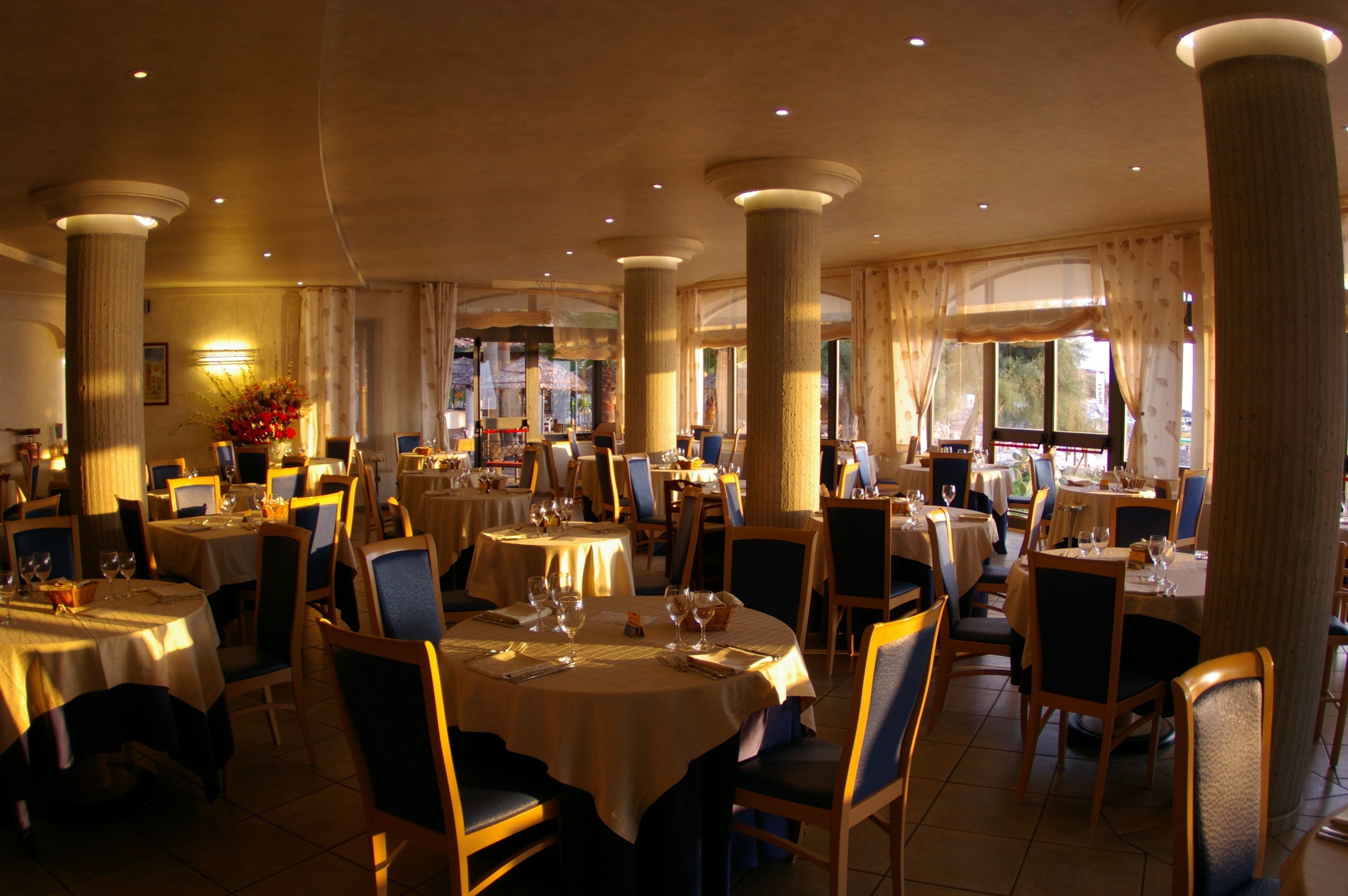 A spacious restaurant with round tables, chairs, and a warm ambiance.