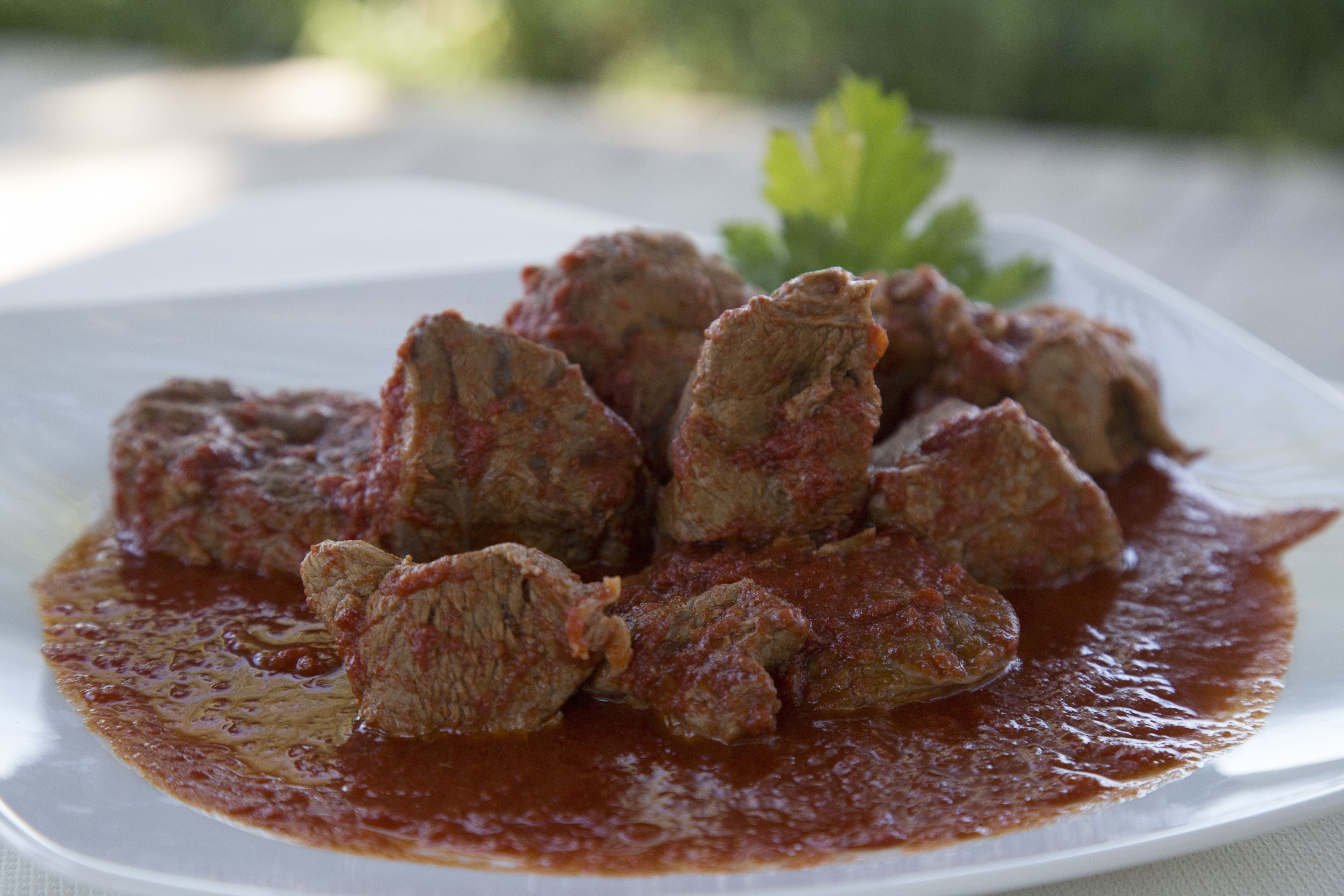 A plate of meatballs in tomato sauce with a garnish of parsley.