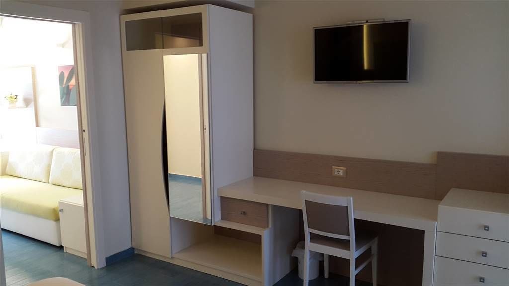 Une petite chambre comprenant un lit, un bureau, une chaise et un téléviseur.