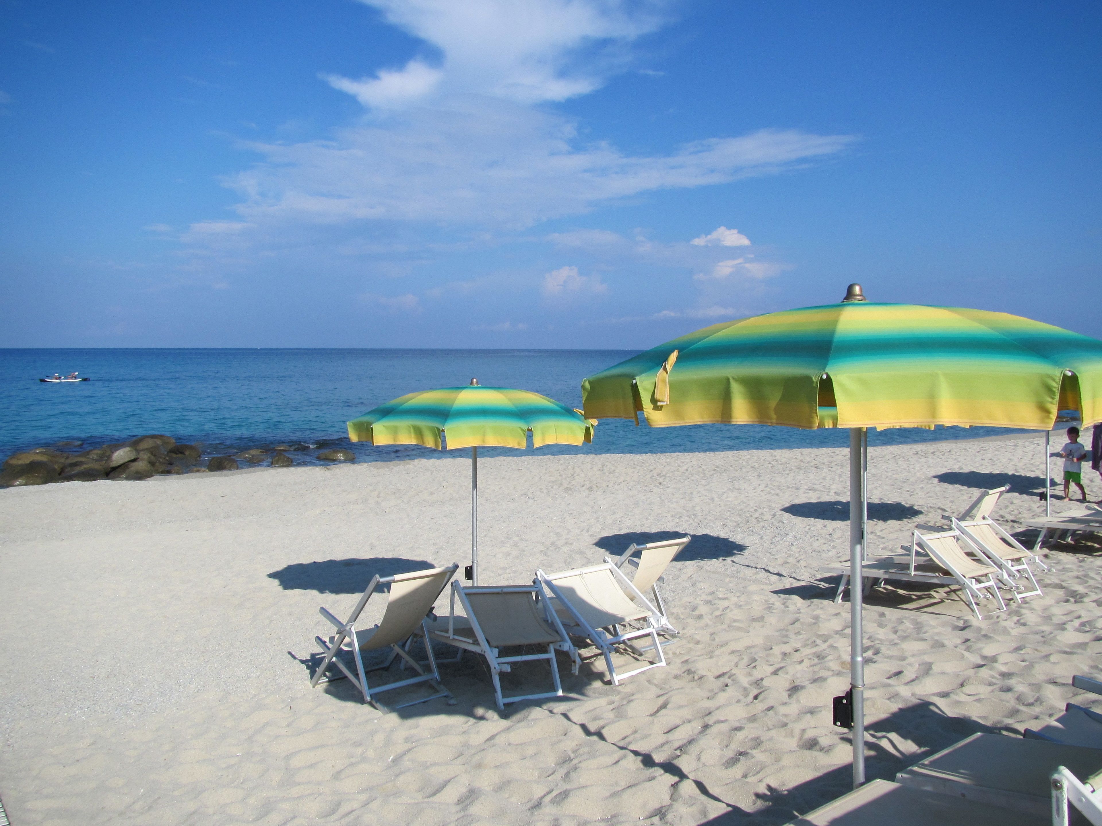 Une plage avec de nombreux parasols et des chaises longues.