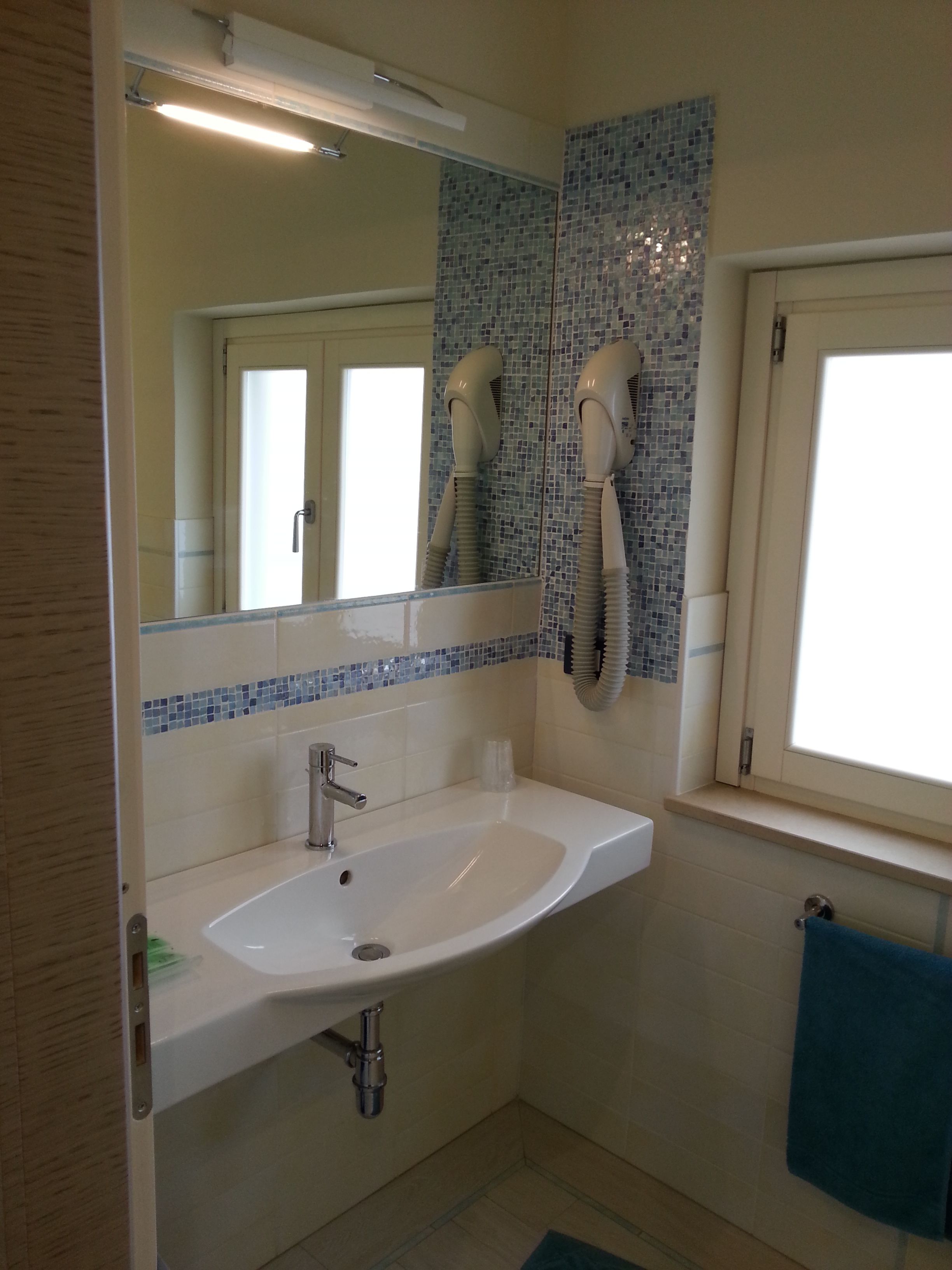 A bathroom with a white sink, a mirror, and a window.