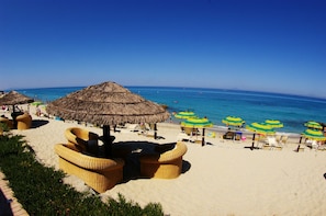 A beach with thatched umbrellas, wicker lounge chairs, and a clear view of the ocean. - Villaggio Il Gabbiano (Ricadi)