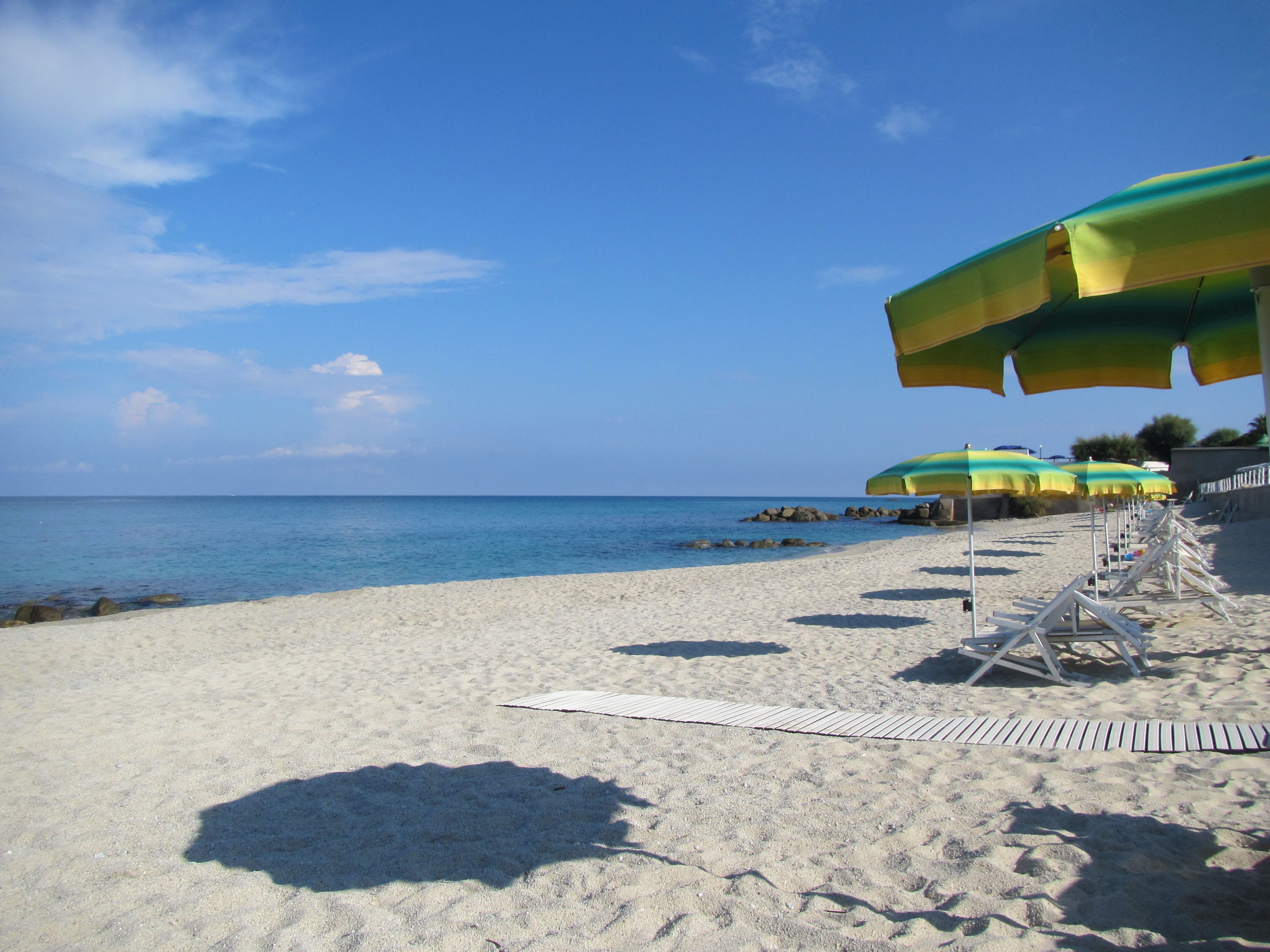 Una spiaggia con file di ombrelloni e lettini.