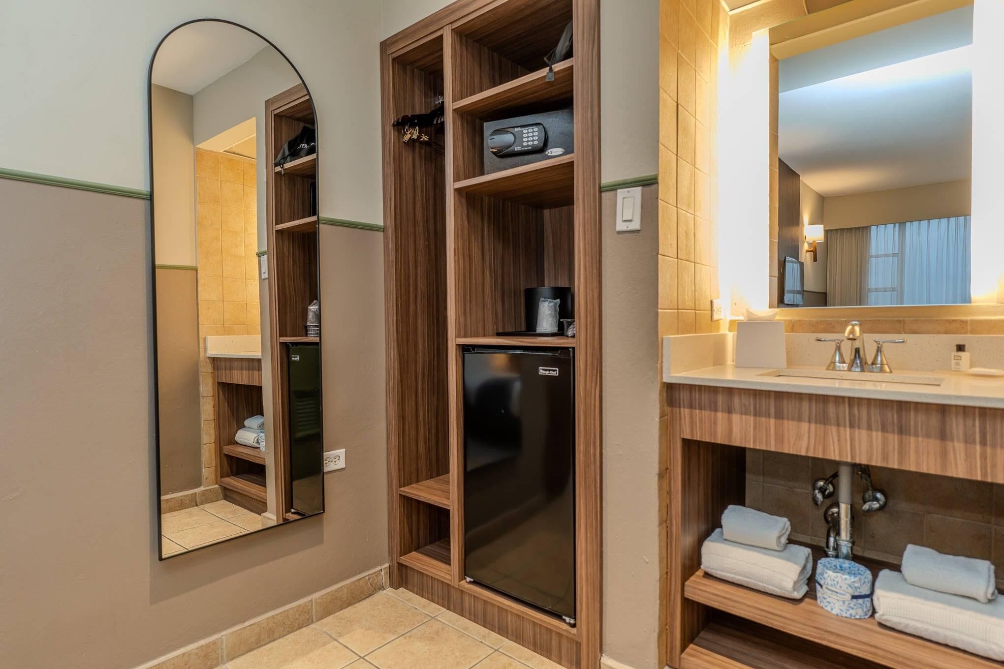 Ein modernes Badezimmer mit einem Holzwaschtisch, einem eingebauten Kühlschrank und einem großen Spiegel.