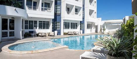 Un hotel moderno con piscina, zona de estar al aire libre y balcones.
