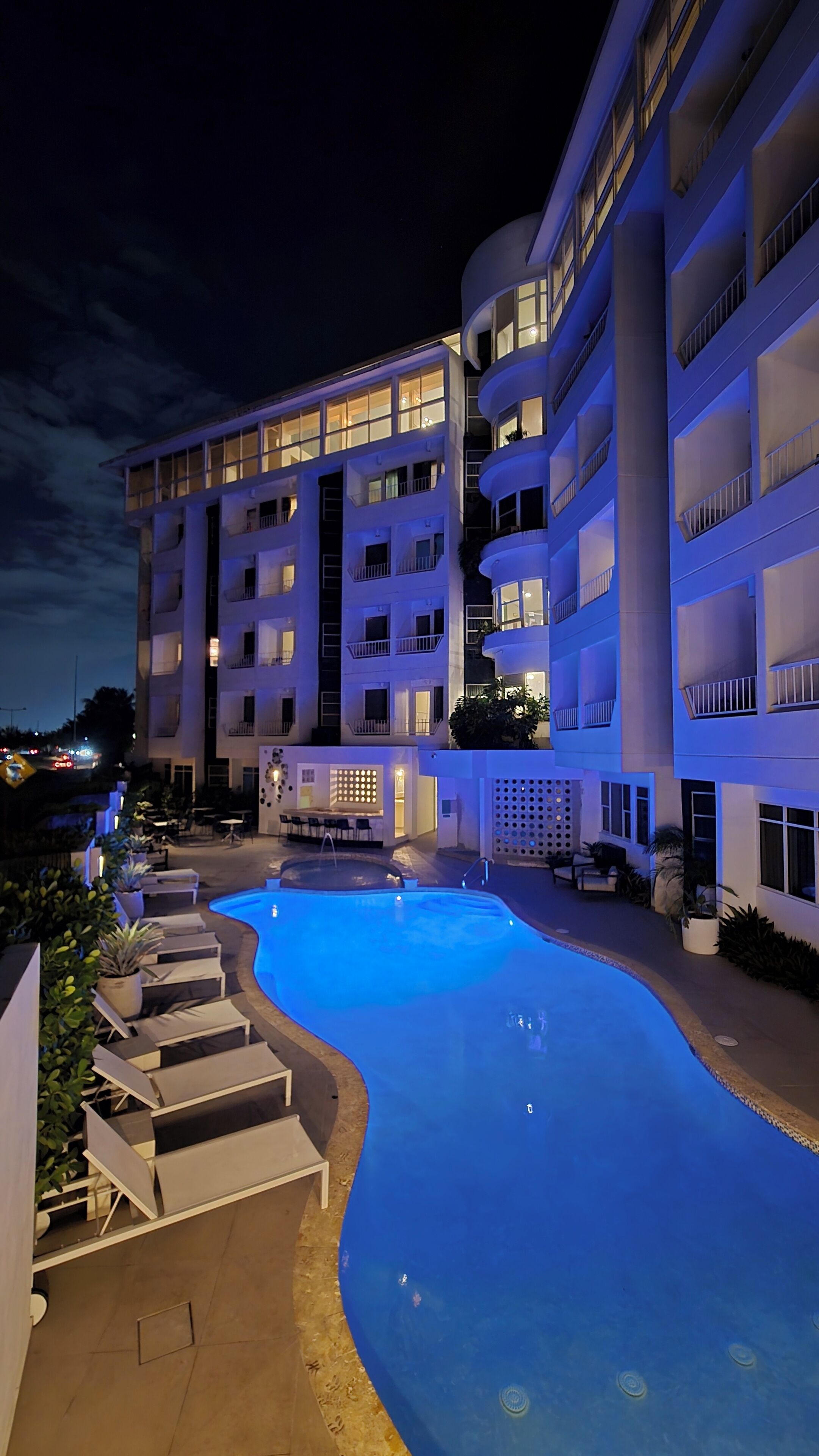 Un hôtel à plusieurs étages doté d’une piscine, d’un espace extérieur aménagé et d’une façade bien éclairée.