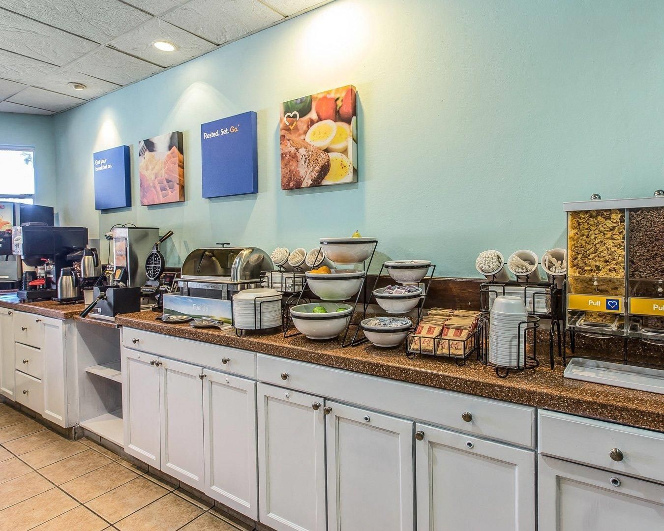 A breakfast buffet area with various food items and a coffee station.
