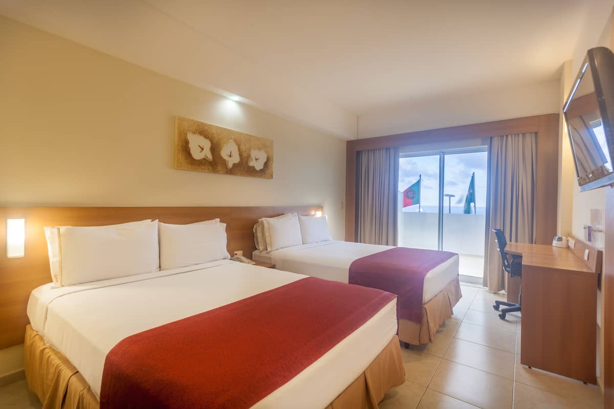 A hotel room with two beds, a desk, and a television.