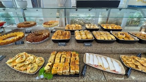 A buffet with various baked goods and dishes, including bread, pastries, and a salad. - Praiamar Ponta Negra Hotel (Natal)