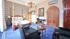 A hotel room with a large bed, two armchairs, a small table, a chandelier, and a wooden wardrobe. - Hotel Windsor (Düsseldorf)