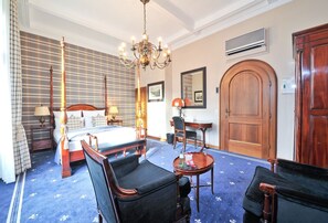 A hotel room with a large bed, two armchairs, a small table, a chandelier, and a wooden wardrobe. - Hotel Windsor (Düsseldorf)