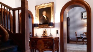 A grand staircase, a wooden console table with a lamp, and a framed portrait above it. - Hotel Windsor (Düsseldorf)