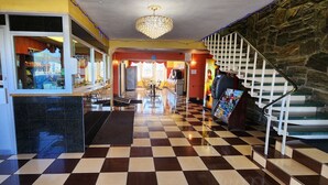 A hotel lobby with a checkered floor, a staircase, a reception desk, and a chandelier. - Townhouse Inn & Suites (Elmwood Park)