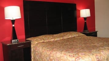 A hotel room with a large bed, two bedside tables, and a red wall.