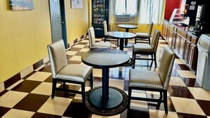 A restaurant with checkered flooring, round tables, and chairs. - Townhouse Inn & Suites (Elmwood Park)
