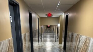 A corridor with marble flooring and beige walls. - Townhouse Inn & Suites (Elmwood Park)