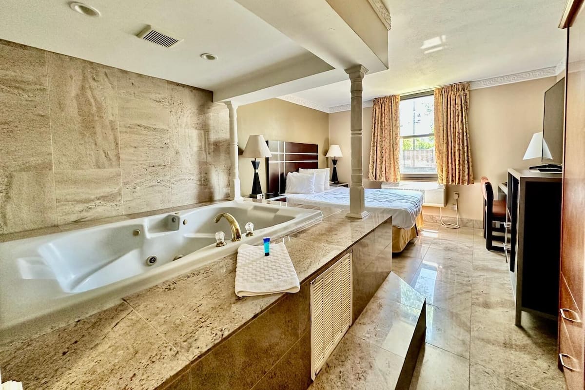 A hotel bathroom with a large bathtub, a sink, and a vanity area.