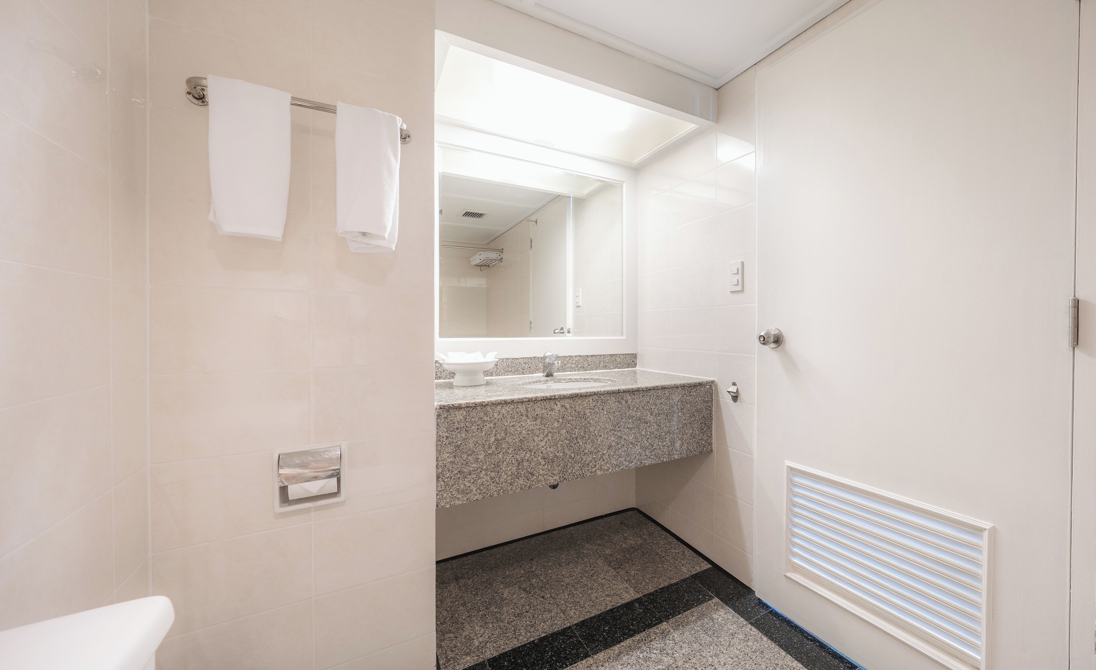 A bathroom with a white sink, mirror, and towel rack.
