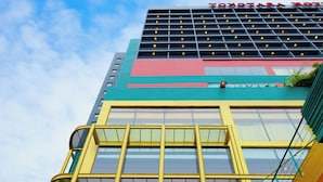 A hotel with a modern design, featuring a prominent glass facade and a red and yellow color scheme.