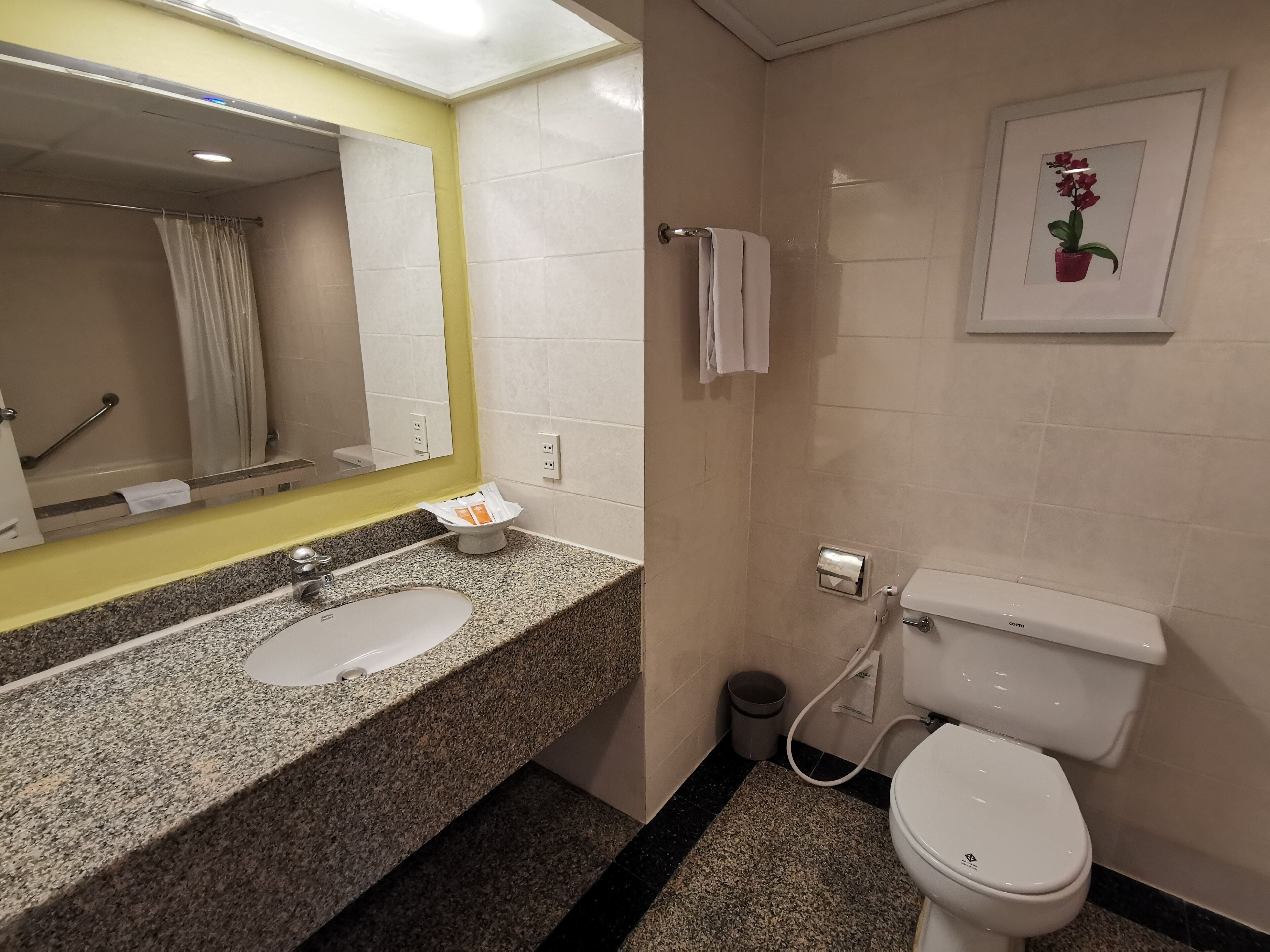 A bathroom with a granite countertop, a white sink, a toilet, and a shower area.