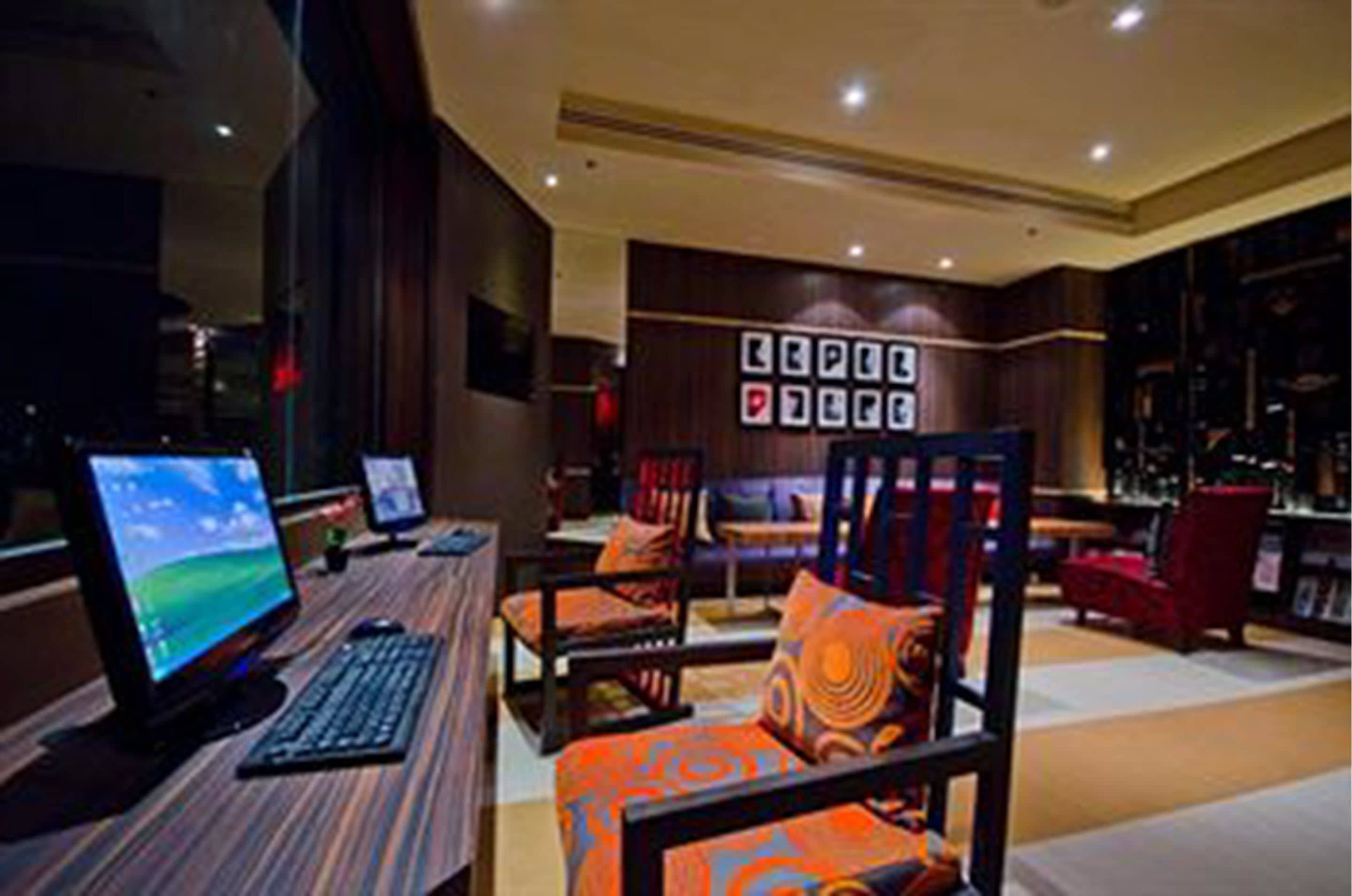 A modern hotel lobby with a long reception desk, comfortable seating area, and a wall-mounted display of framed pictures.