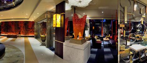 A spacious lobby with a central column, seating areas, and a reception desk.