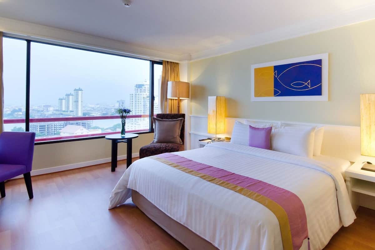 Une chambre d’hôtel avec un grand lit, une chaise, une table de chevet, une lampe et une vue sur la ville.